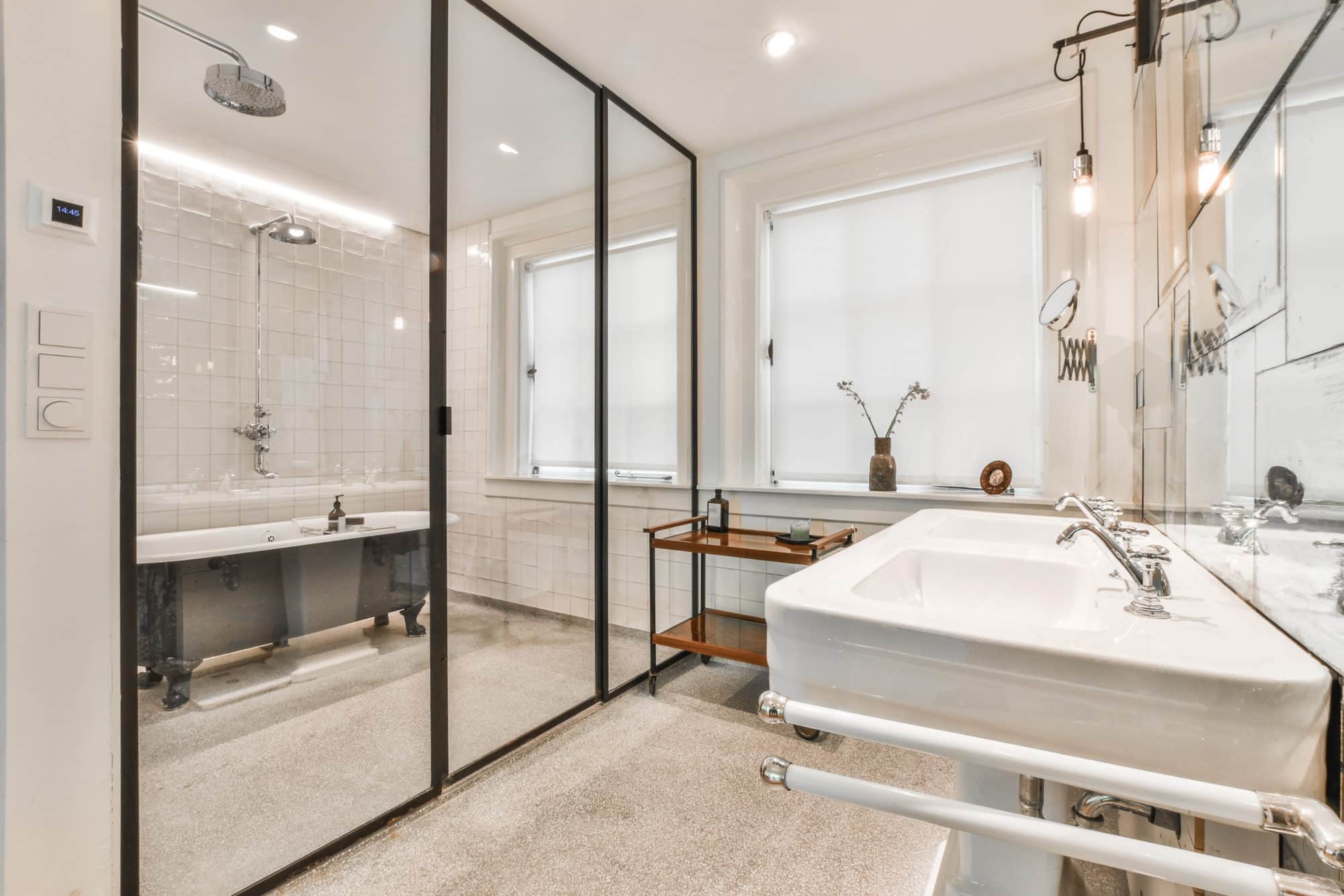 A bathroom with glass tub enclosures and a sink.