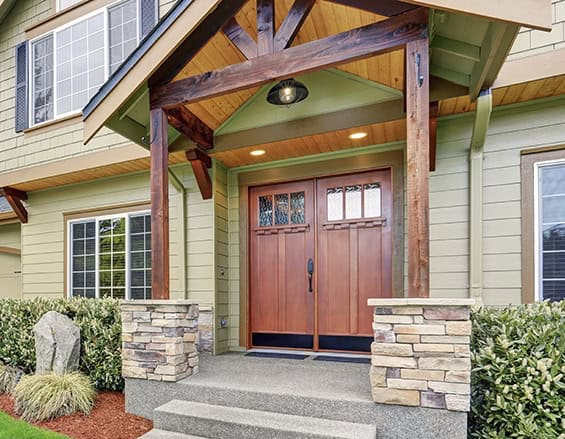 A house with a wooden front door in need of repair and stone steps.