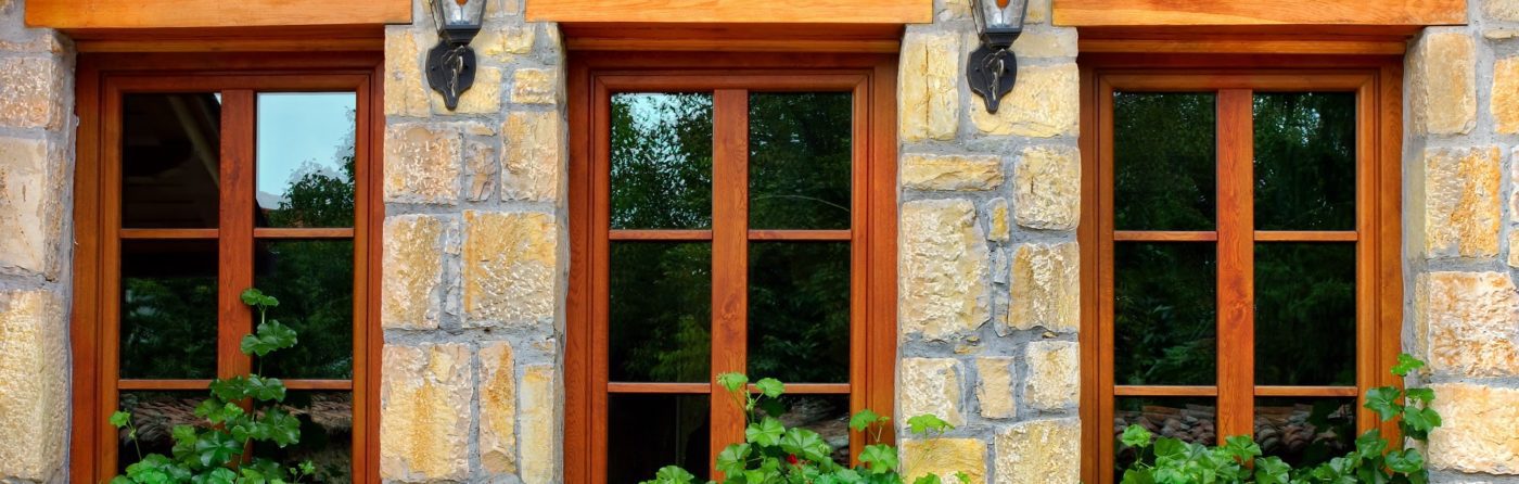 Lovely wooden windows with flowers on old stone wall