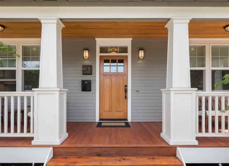 The front porch of a home with wooden railings and white trim.