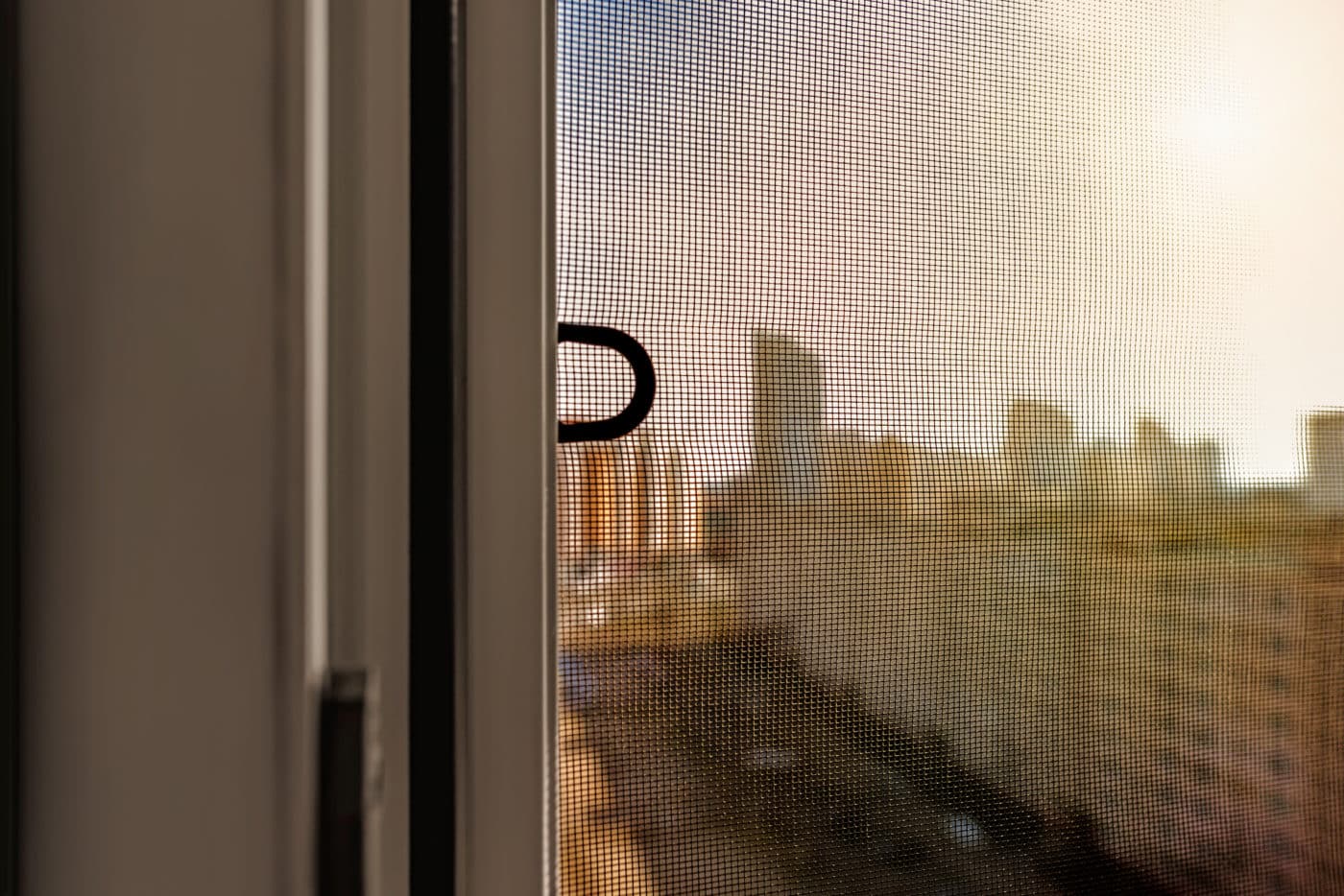 A window with a view of a city, enhanced by solar screens.