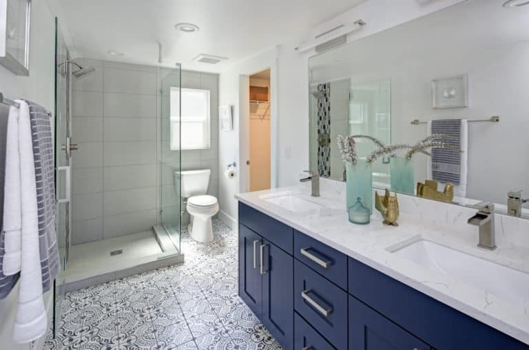 A bathroom with blue cabinets and a glass shower update.