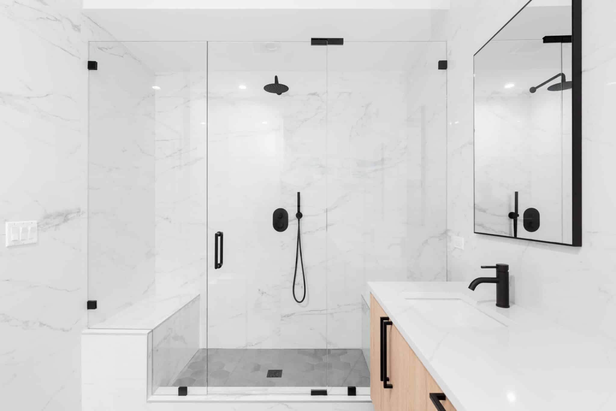 A white and black bathroom with a marble shower stall featuring shower glass.